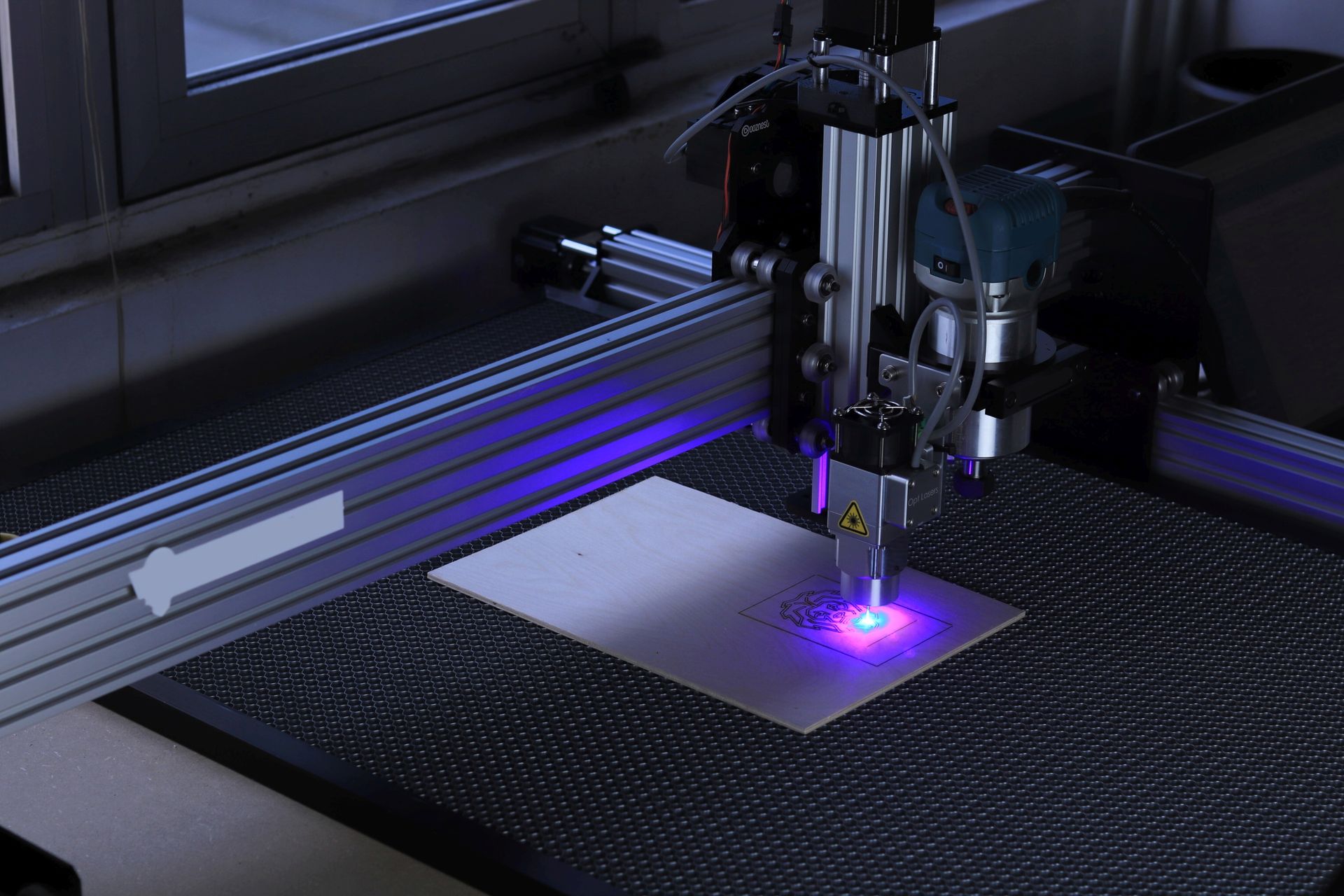 tête de graveuse laser CNC en train de graver une pièce en bois, motif qui se dessine en direct